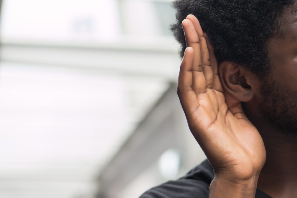 Man holding his hand to his ear to listen.